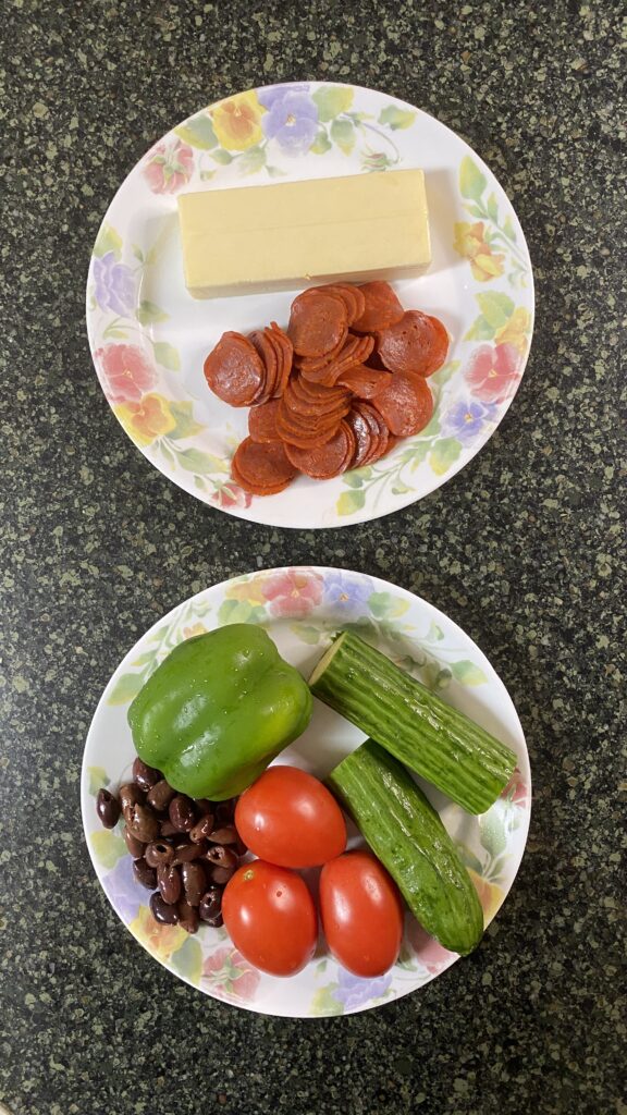 Perspective shot on pepperoni, cheese, green pepper, tomatoes, cucumber, and Kalamata olives. 
