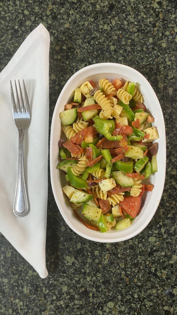 Aerial shot of cold pasta salad in serving dish with fork and napkin. 